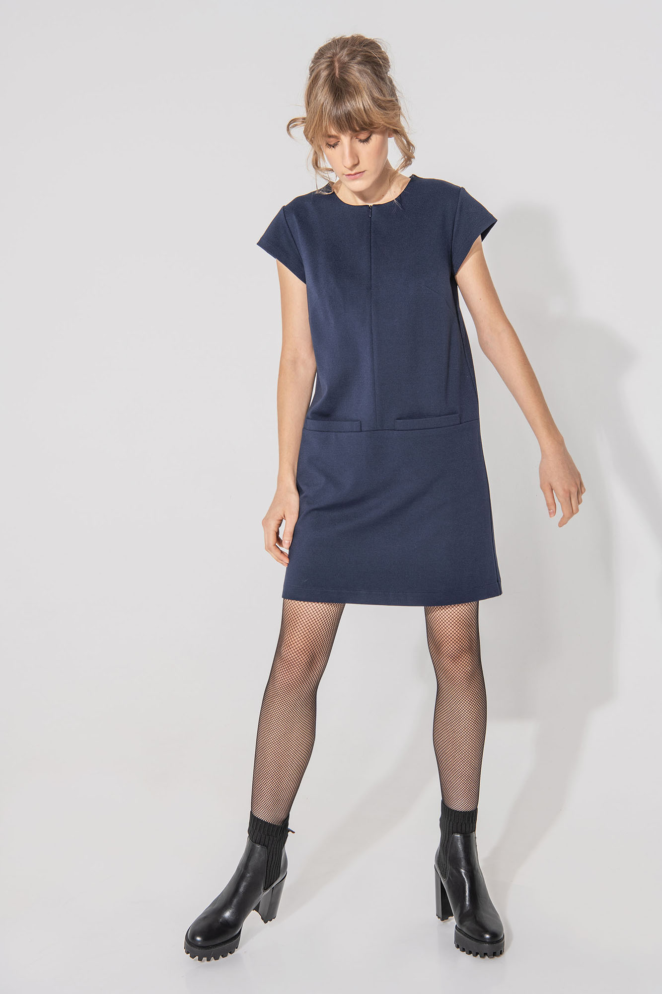 Dark blue trapeze dress with big front pockets looking down • Sassa Björg